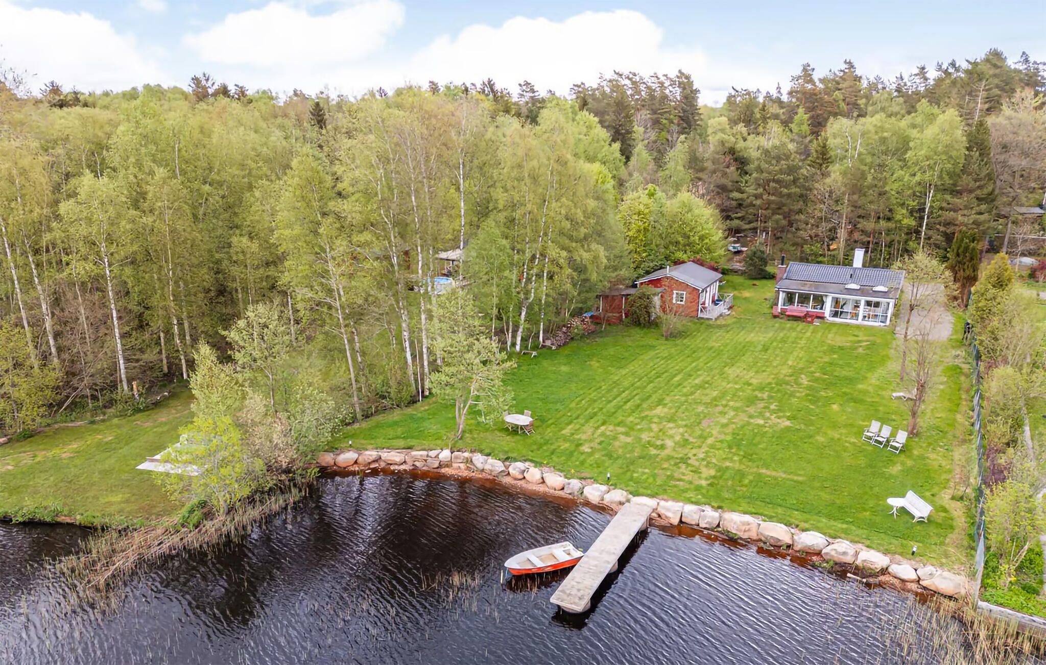 A lakeside property with a dock, a house, and a well-maintained lawn.