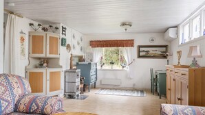 A cozy living room with patterned sofas, a wooden coffee table, a dining area with a table and chairs, and a kitchen area with cabinets and a refrigerator. - 3 bedroom beautiful home in Ljungbyhed (Ljungbyhed)