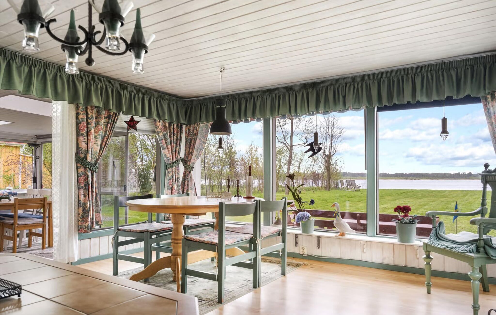A dining area with a table and chairs, a view of a lake, and a chandelier.