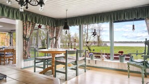 A dining area with a table and chairs, a view of a lake, and a chandelier. - 3 bedroom beautiful home in Ljungbyhed (Ljungbyhed)