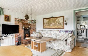 Ein Wohnzimmer mit Kamin, Fernseher, einer Couch und einem Bild an der Wand.