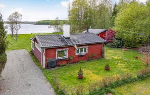 Ein rotes Haus mit Schornstein, einer kleinen Veranda und Blick auf einen See.