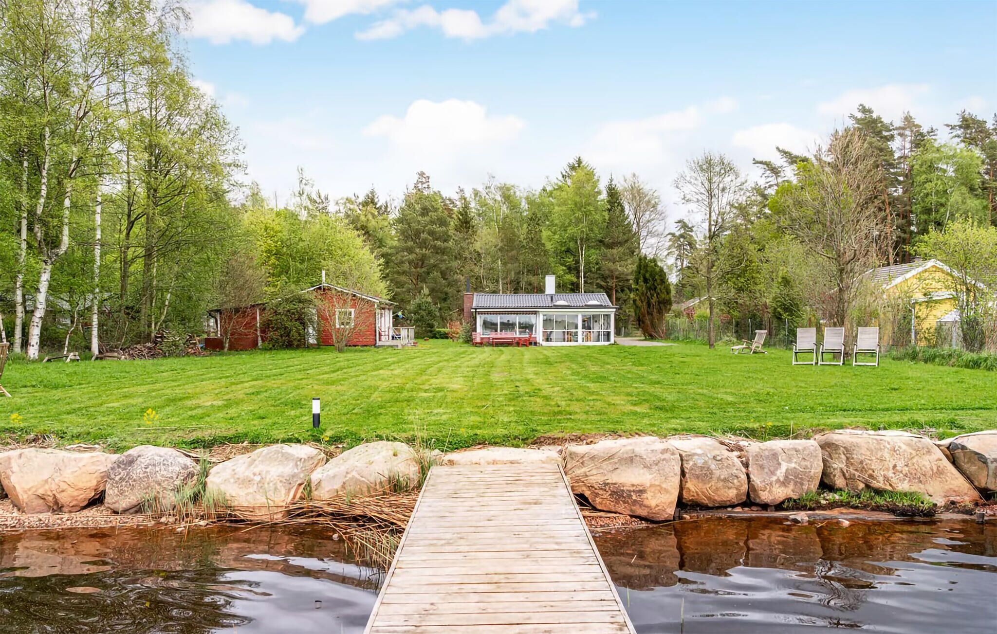 A lakeside property with a wooden dock, a house, and a small shed.