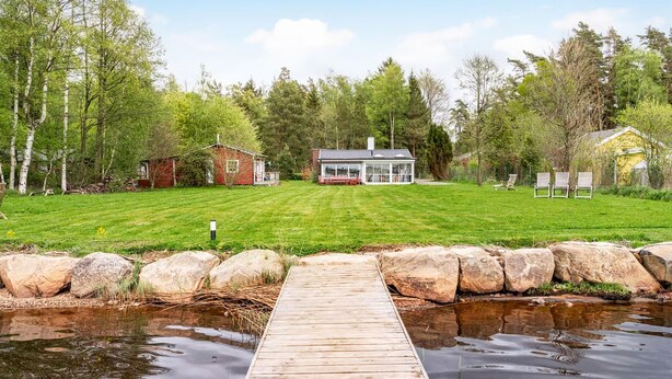 A lakeside property with a wooden dock, a house, and a small shed. - 3 bedroom beautiful home in Ljungbyhed (Ljungbyhed)