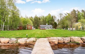 A lakeside property with a wooden dock, a house, and a small shed. - 3 bedroom beautiful home in Ljungbyhed (Ljungbyhed)