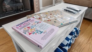 Un comodino bianco con un libro intitolato 'HOSPITABLE HOSTS' e un libro su 'BEACHES'.