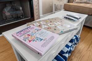 Ein weißer Nachttisch mit einem Buch mit dem Titel 'HOSPITABLE HOSTS' und einem Buch über 'BEACHES'.