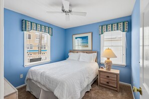 Une chambre à coucher avec un lit, une table de chevet, une lampe et un ventilateur de plafond.