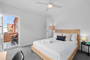 A hotel room with a bed, a bedside table, a lamp, a chair, and a view of the outside. - Bright 2BDR Bondi Junction Home with Parking (Bondi Junction)