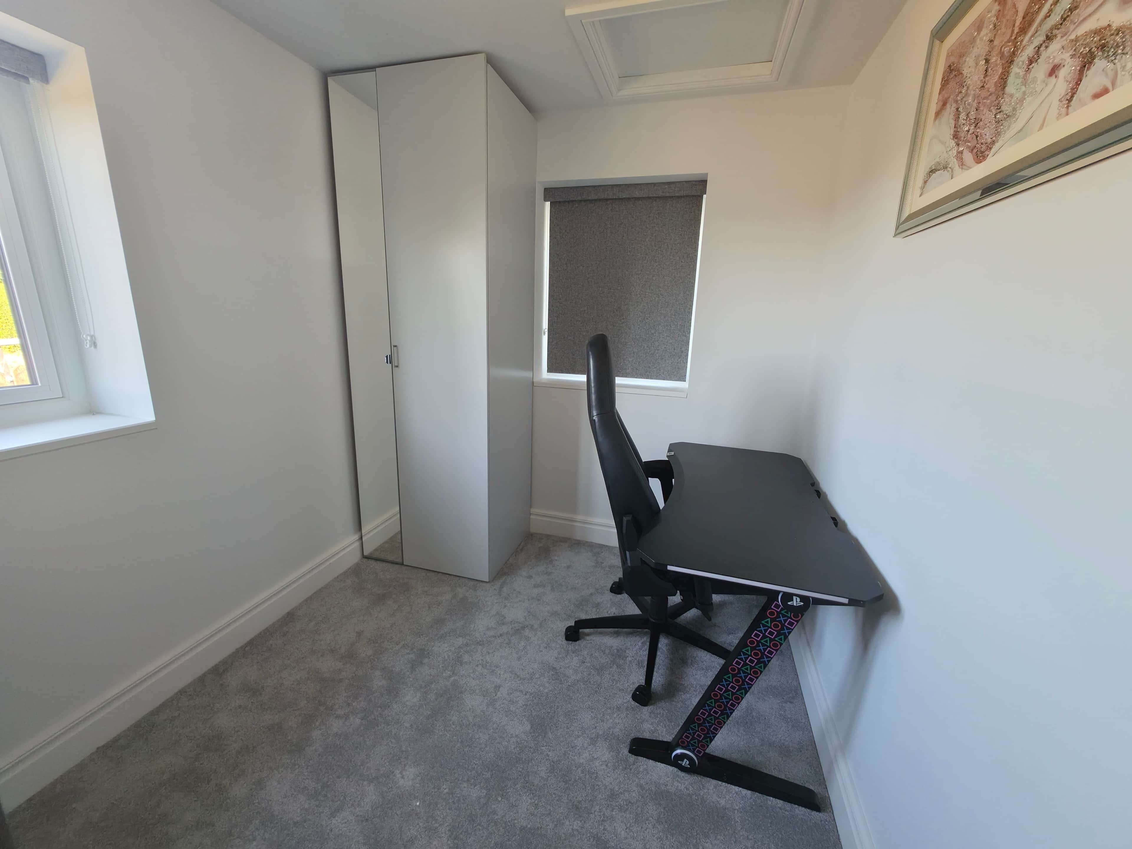 Una habitación con escritorio, silla y ventana.