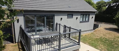 A modern house with a deck, large windows, and a fenced patio area.