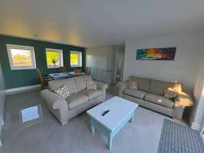 A living room with a sofa, a coffee table, and a dining area with a table and chairs.