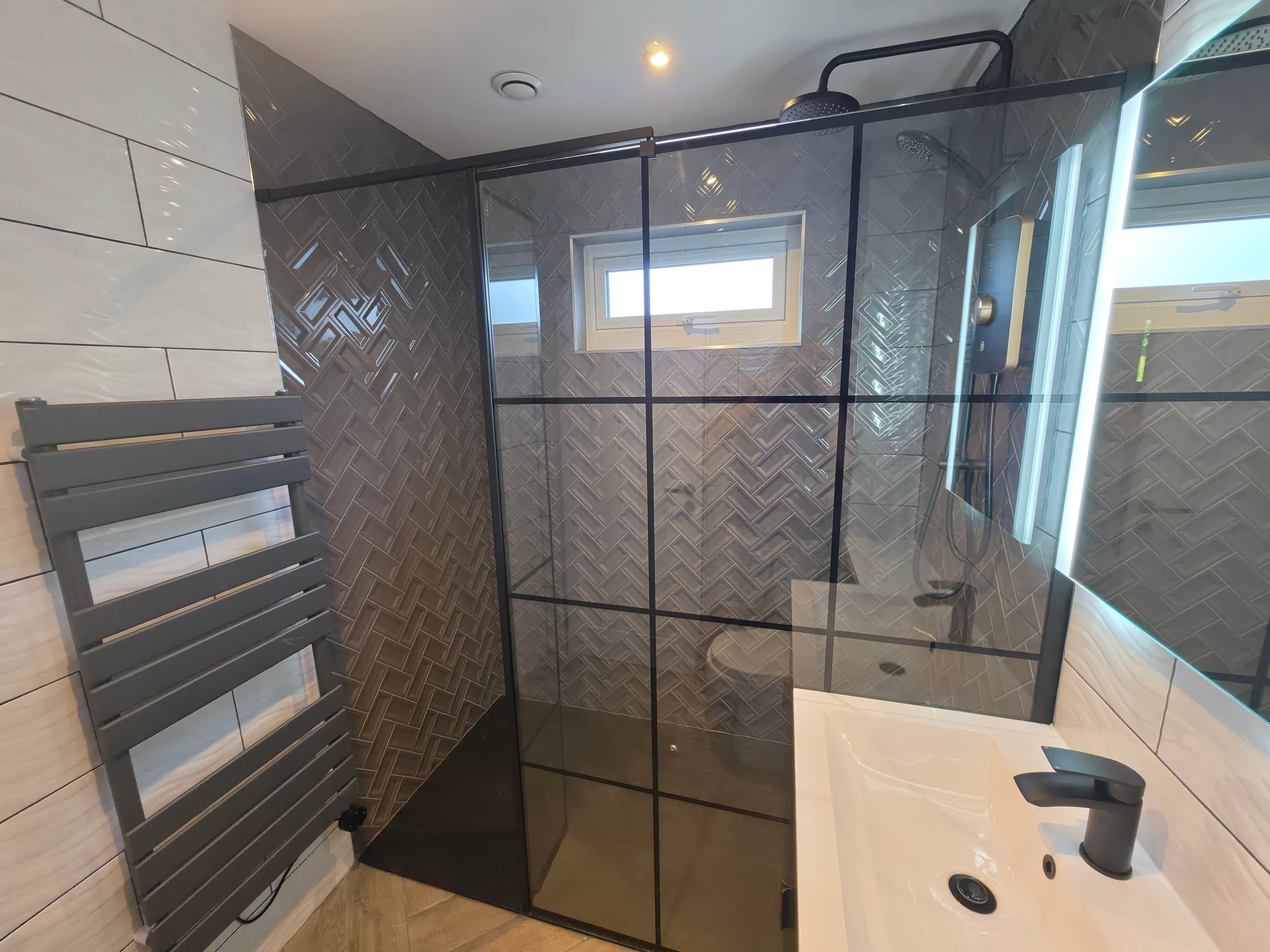 A modern bathroom with a glass shower enclosure, a built-in toilet, and a white sink.