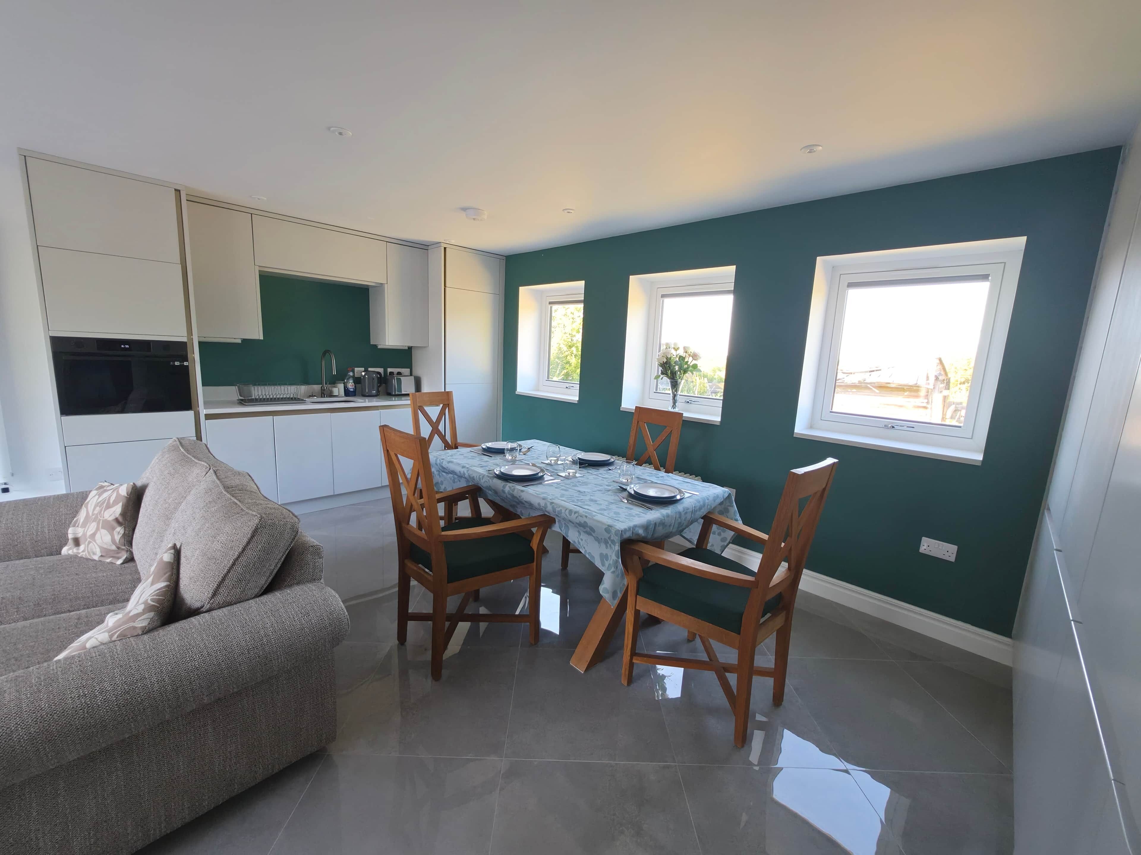 A modern kitchen with white cabinets and a dining area with a table set for four.