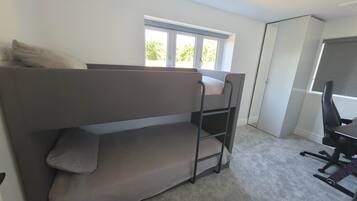 Un letto a castello con scrivania e sedia, una finestra e una porta.