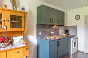 A compact kitchen with a sink, a coffee maker, and a washing machine.