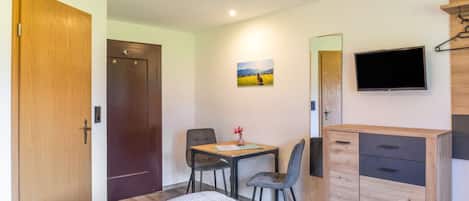 Une chambre comprenant un lit, un bureau avec une chaise, une télévision et une armoire.