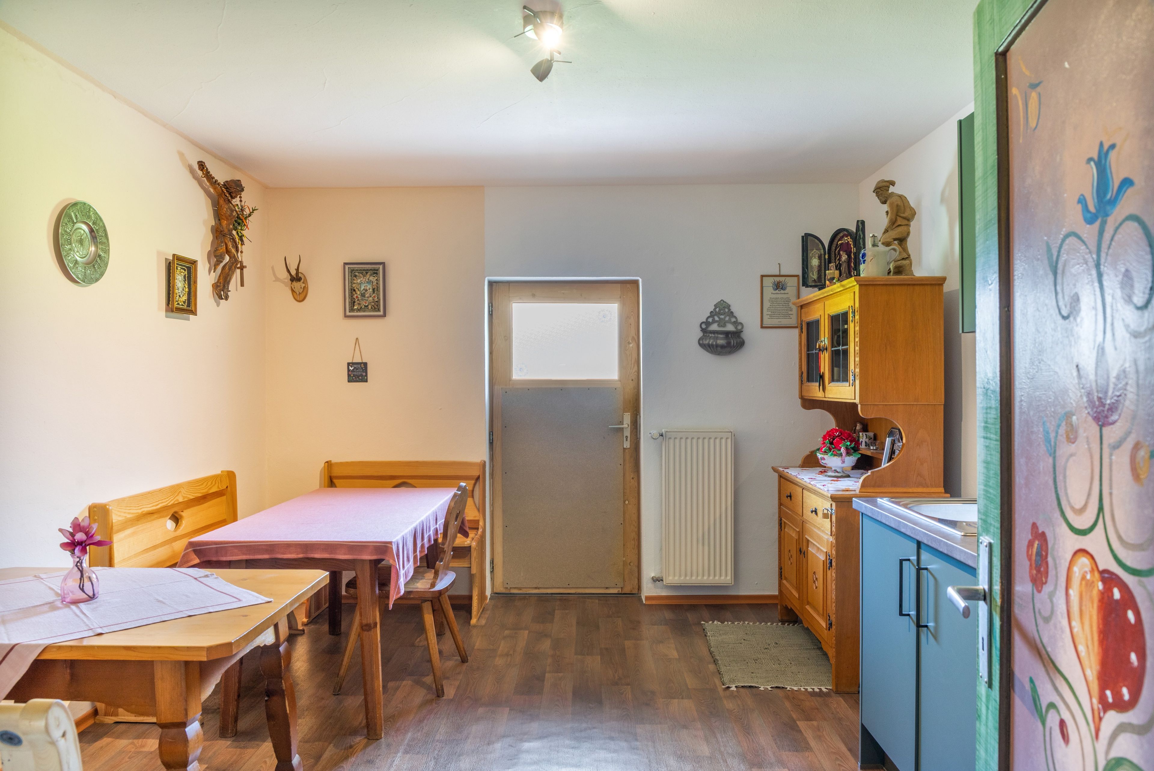 Une petite cuisine accueillante, avec des meubles en bois, une table à manger et un meuble contenant des objets décoratifs.