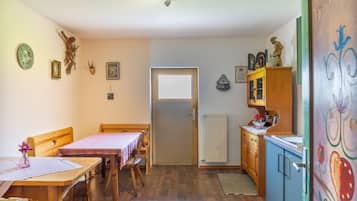 Une petite cuisine accueillante, avec des meubles en bois, une table à manger et un meuble contenant des objets décoratifs.