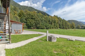 A building with a metal structure, a small shed, and a grassy field with cows in the distance. - Room "Zimmer 2 Schulerhof" with Mountain View and Wi-Fi (Oberau)