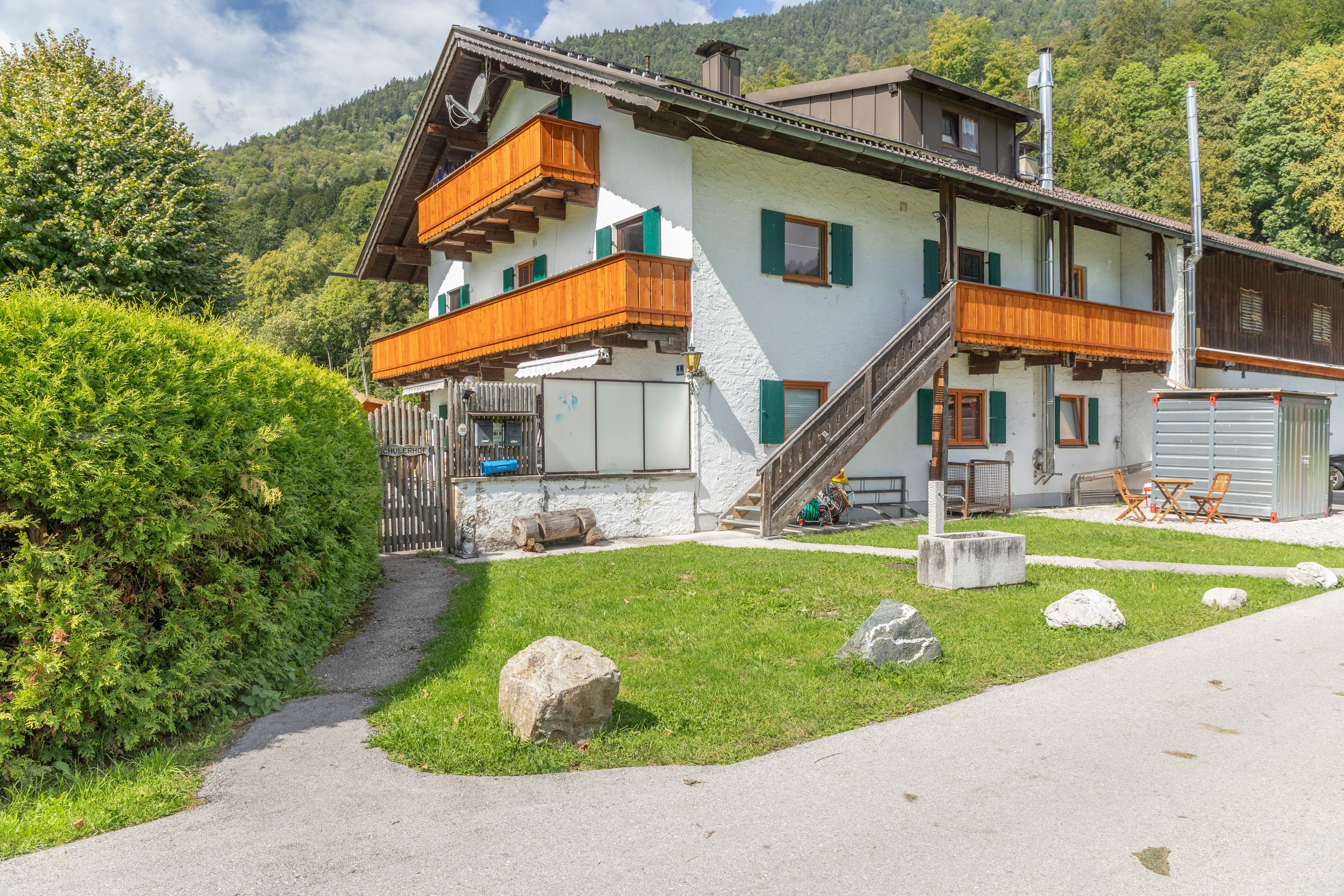 Eine zweistöckige Chalet mit Holzbalkon, Steinstufen und Bergblick.