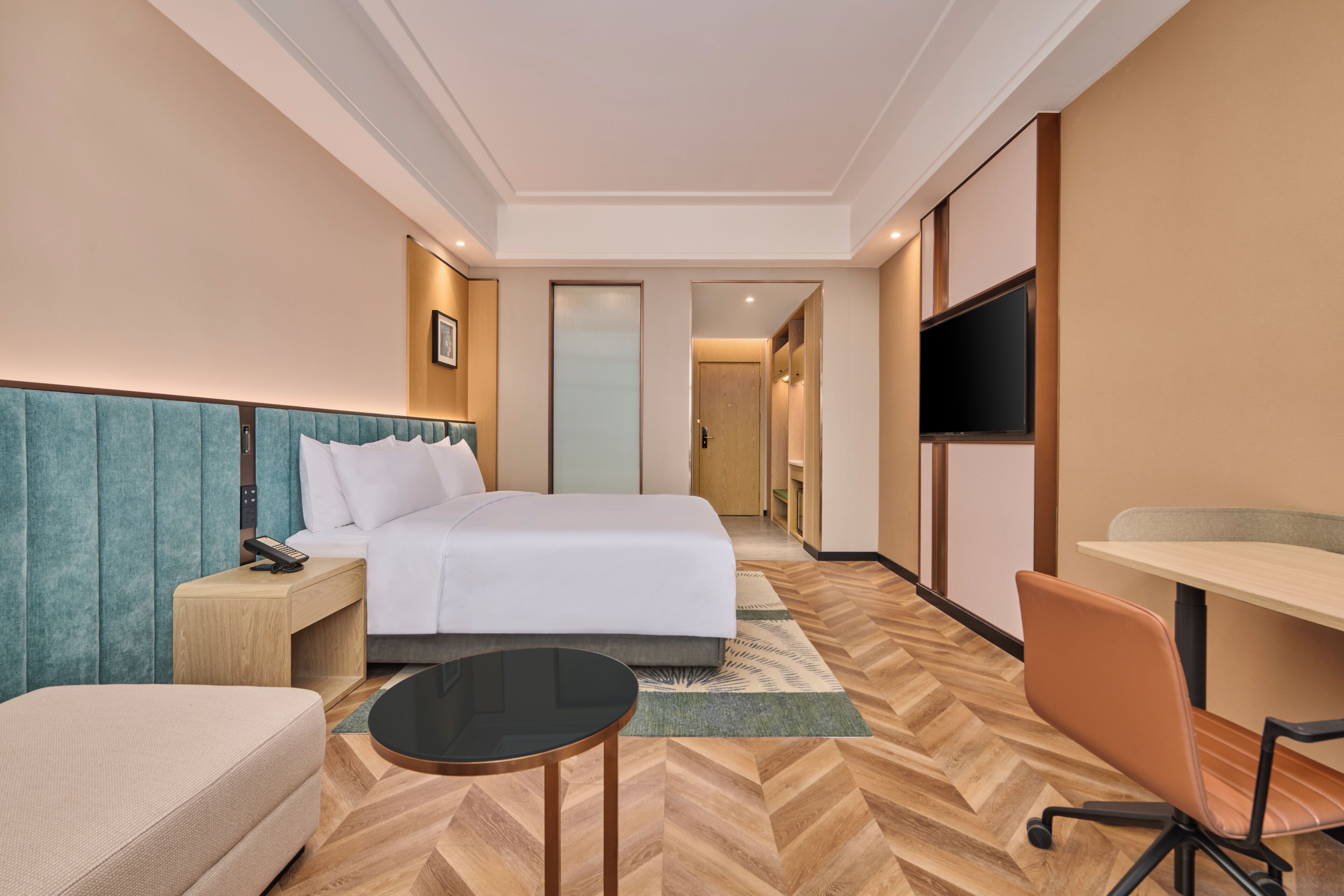 Habitació d'hotel amb llit, taula de nit, cadira, escriptori i televisió.