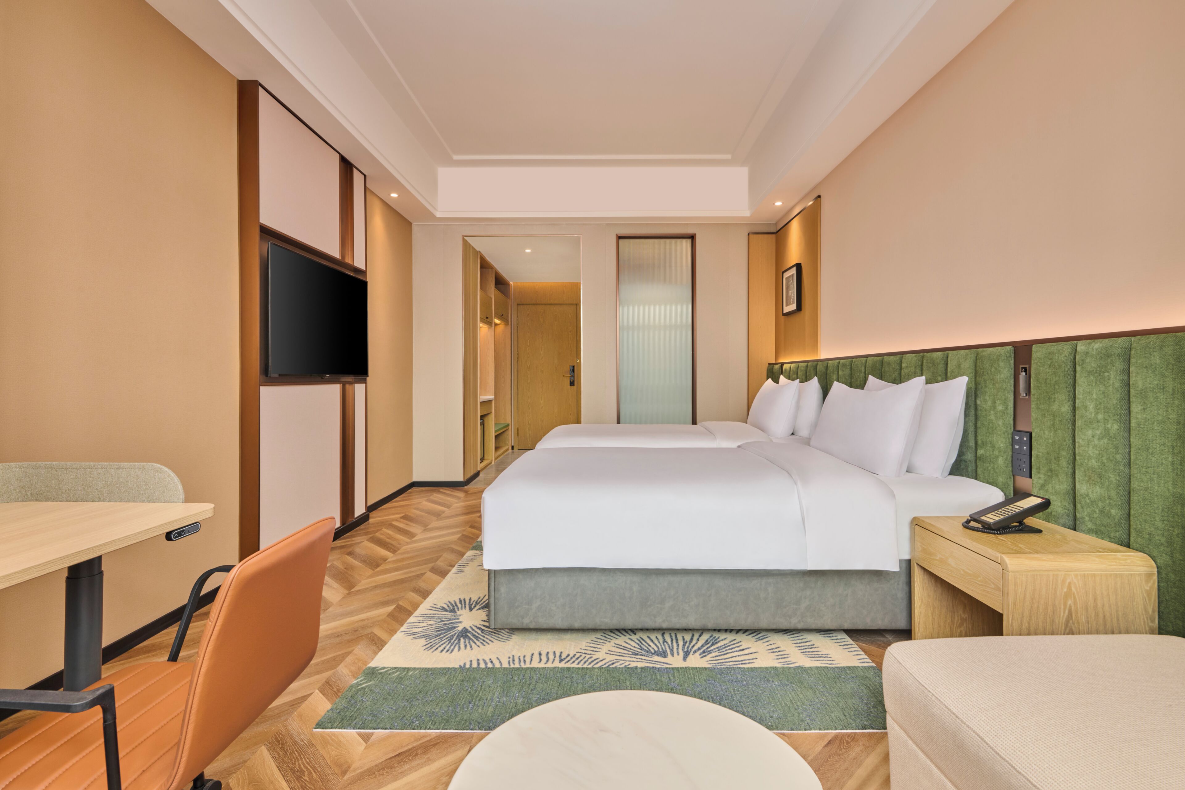 Ein Hotelzimmer mit Bett, Schreibtisch, Stuhl, Fernseher und Telefon.