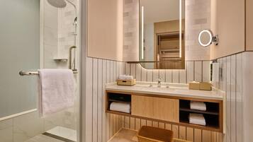 A modern bathroom with a glass-enclosed shower, a vanity with a mirror, and a wicker basket.
