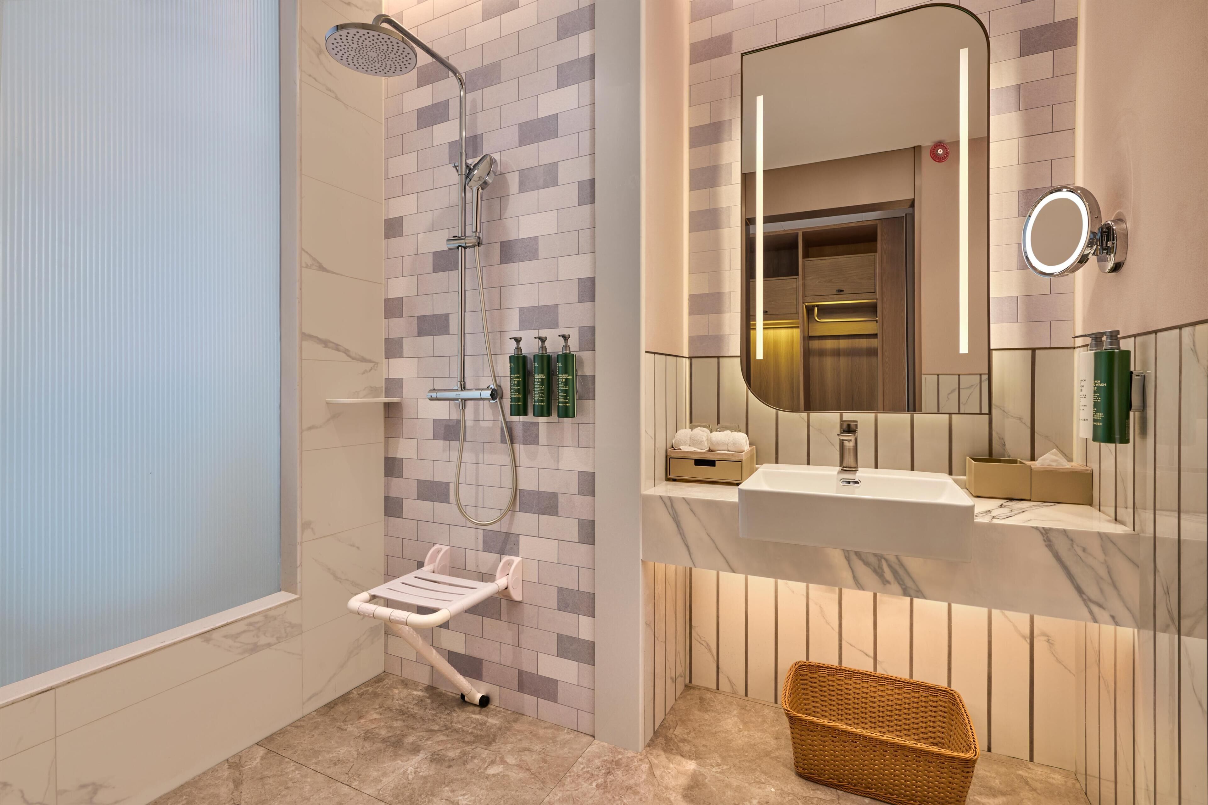 A modern bathroom with a shower, a vanity with a mirror, and a wicker basket.