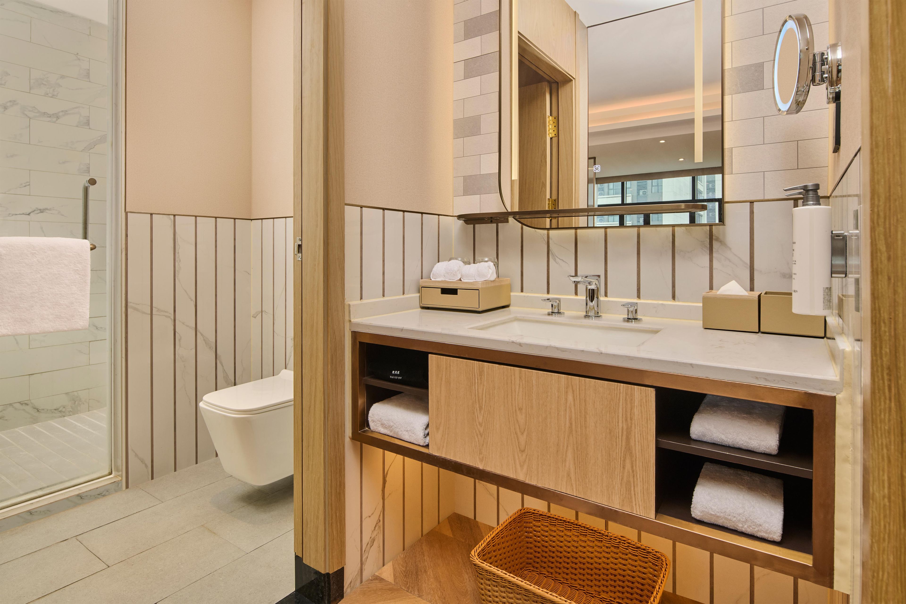 Un baño moderno con cabina de ducha de vidrio, inodoro, tocador con espejo y lavabo.