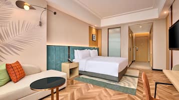 Een hotelkamer met een bed, een bank, een tafeltje, een televisie en een bureau.