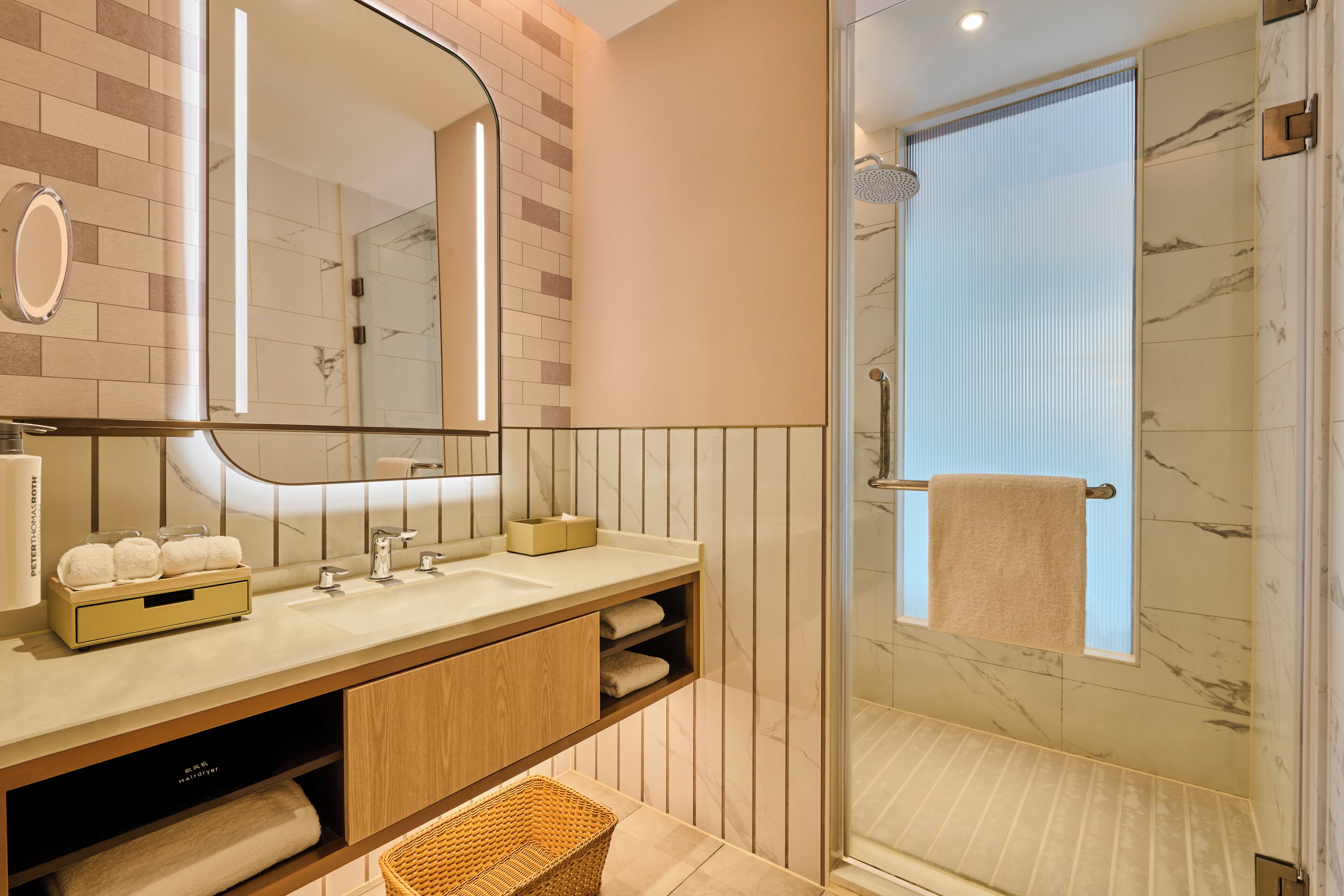 A modern bathroom with a glass-enclosed shower, a vanity with a mirror, and a towel rack.