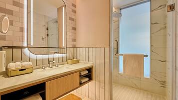 A modern bathroom with a glass-enclosed shower, a vanity with a mirror, and a towel rack.