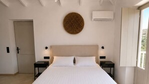 Ein großes Bett mit Kopfteil, zwei Nachttische, eine Wand-Klimaanlage und eine runde Wanddekoration.