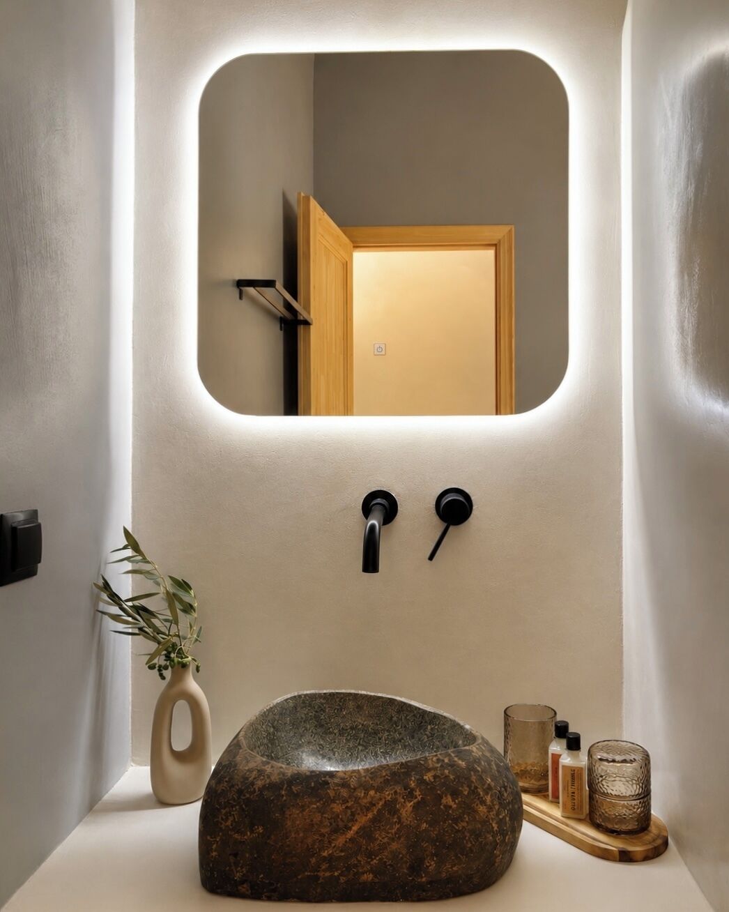 A bathroom with a stone sink, a mirror, and a wooden door.