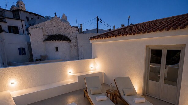 A rooftop pool area with two lounge chairs and a small table, surrounded by white walls and a tiled roof. - Dryope Luxury Living (Kithnos)