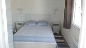 Un dormitorio con una cama, dos mesitas de noche, una lámpara colgante y una ventana con cortinas.