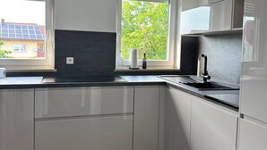 A modern kitchen with white cabinets, a black countertop, a built-in stove, and a window with a view of greenery. - View of Karlstadt Castle (Karlstadt)