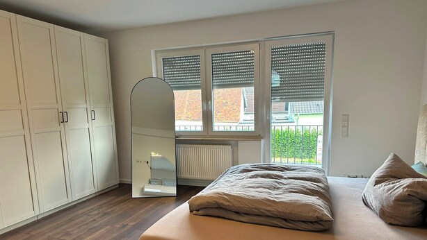 A bedroom with a bed, a wardrobe, a mirror, and a window with blinds. - View of Karlstadt Castle (Karlstadt)