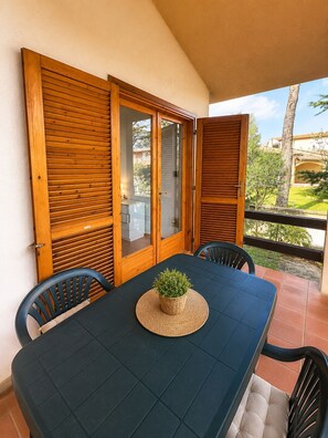 A balcony with a table and chairs, a potted plant, and a view of a residential area. - Casa Vacanze San Teodoro (San Teodoro)