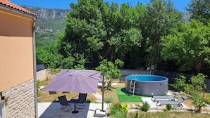 En trädgård med en pool, utemöbler och utsikt över träd och berg.