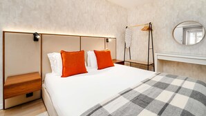 Et moderne hotelværelse med en stor seng, et sengebord, et garderobeskab og et spejl.