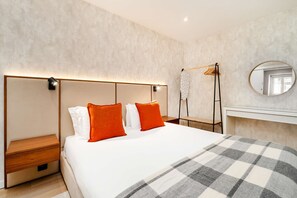 Ein modernes Hotelzimmer mit einem großen Bett, einem Nachttisch, einem Kleiderschrank und einem Spiegel.