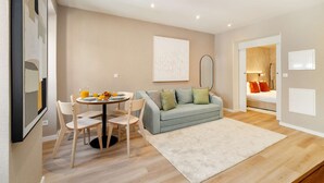 En moderne stue med et rundt spisebord, en sofa og et stort spejl.
