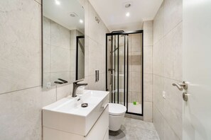 Ein modernes Badezimmer mit Waschbecken, Toilette und einer Duschkabine aus Glas.