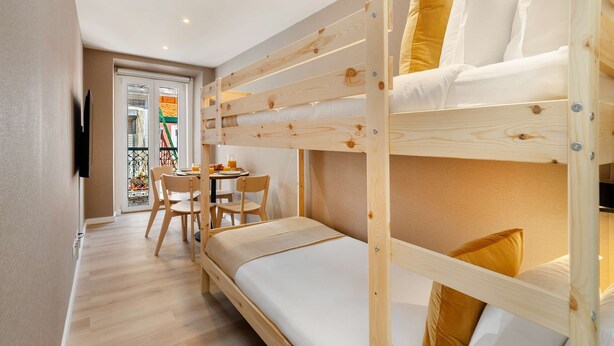 A bunk bed room with a desk and chairs, a television, and a view of the outside. - Cozy Retreat Near Picturesque Rua Verde (Lisboa)