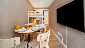 A modern hotel room with a dining area, a bunk bed, and a flat-screen TV. - Cozy Retreat Near Picturesque Rua Verde (Lisboa)