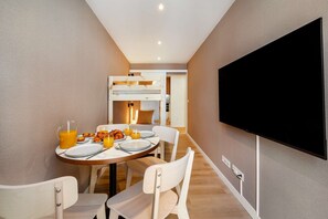 A modern hotel room with a dining area, a bunk bed, and a flat-screen TV. - Cozy Retreat Near Picturesque Rua Verde (Lisboa)