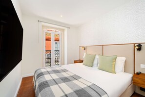 Ein Hotelzimmer mit einem Bett, einem Nachttisch, einer Wandleuchte und einer Tür zu einem Außenbereich.