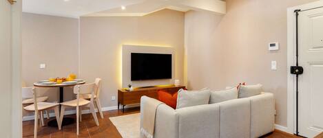 A modern living room with a sofa, TV, dining table, and chairs.